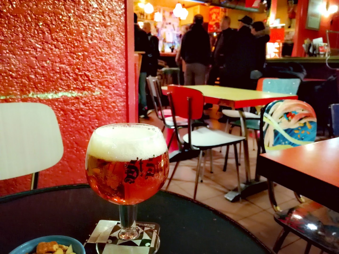 Un verre de bière ambrée devant l’intérieur coloré du bistro